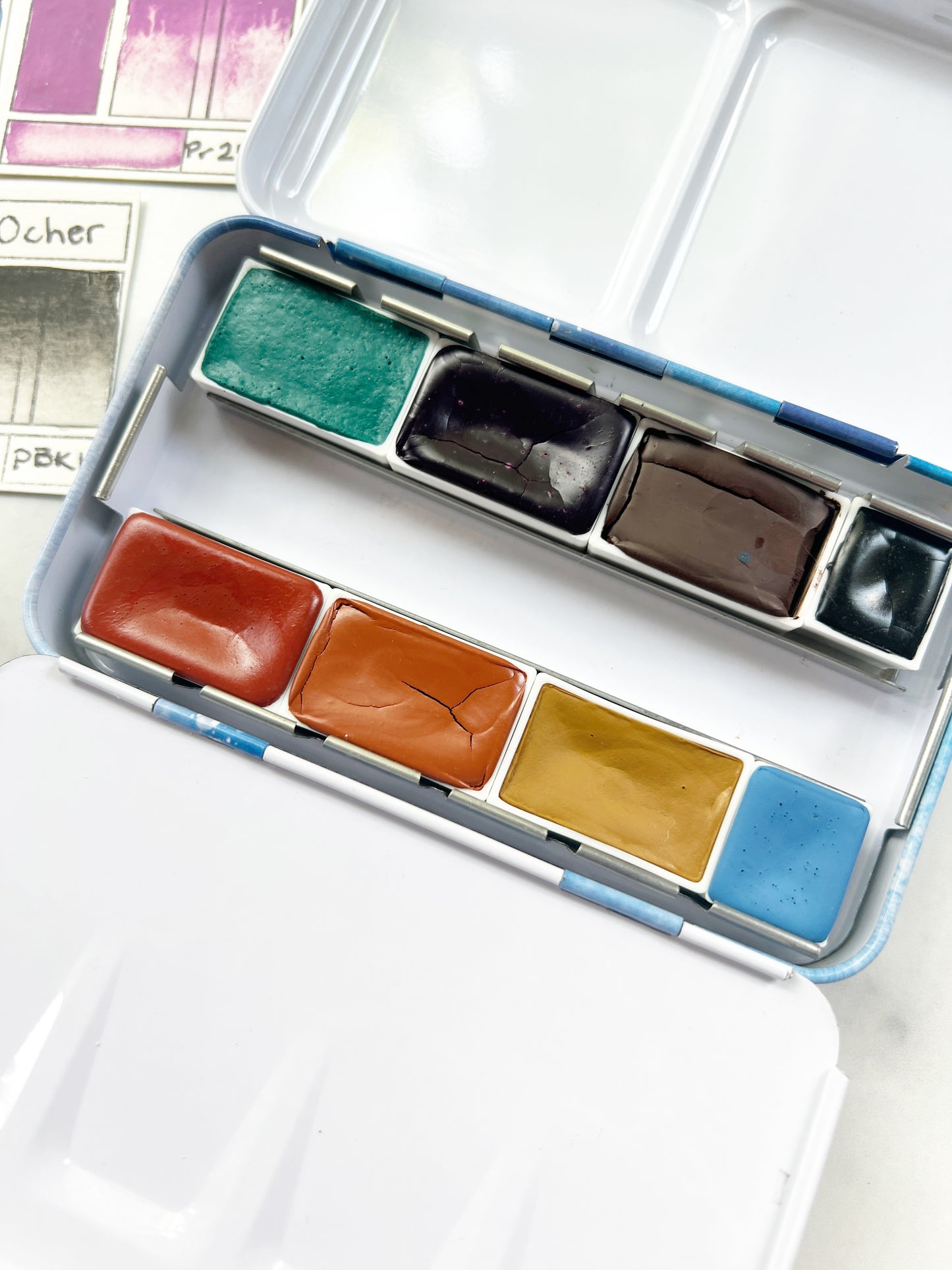 Set of watercolor paints in a metal palette on a white surface
