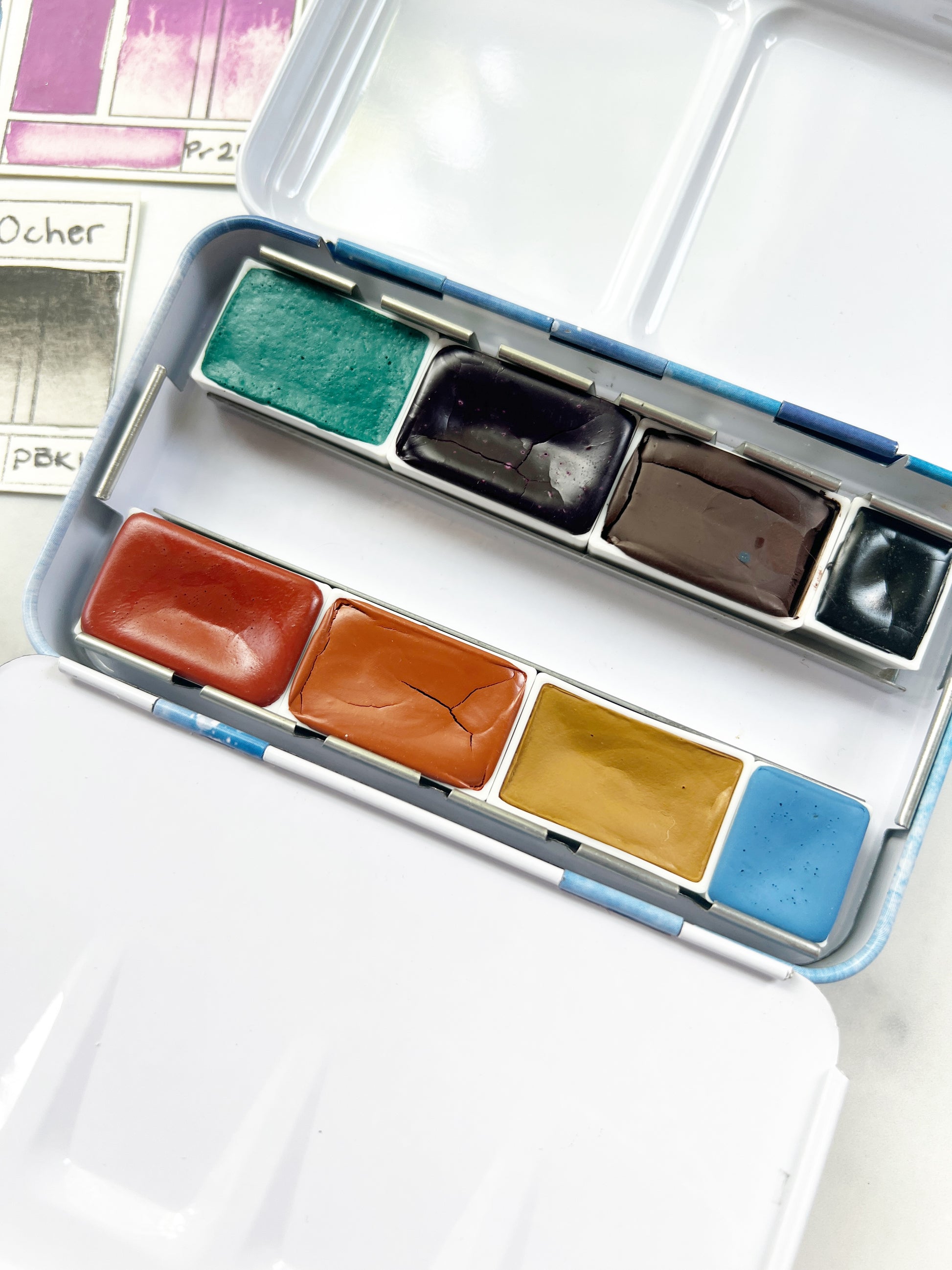 Set of watercolor paints in a metal palette on a white surface