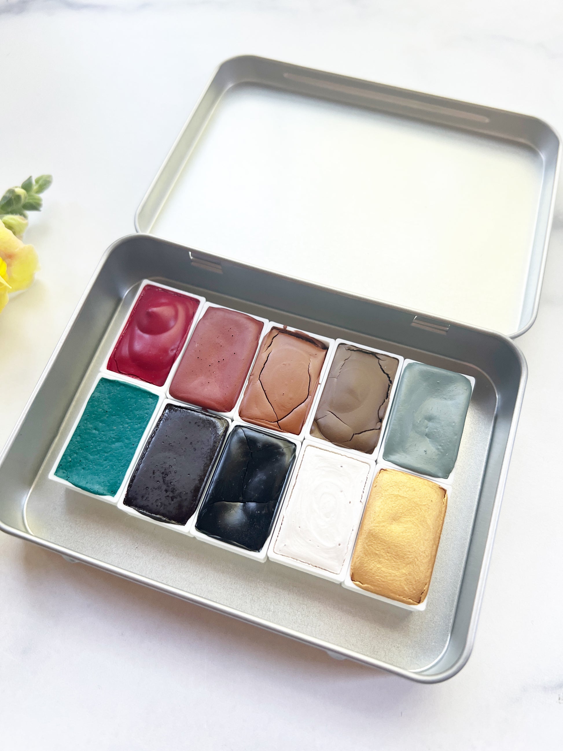 Metallic watercolor palette with various colors on a white background